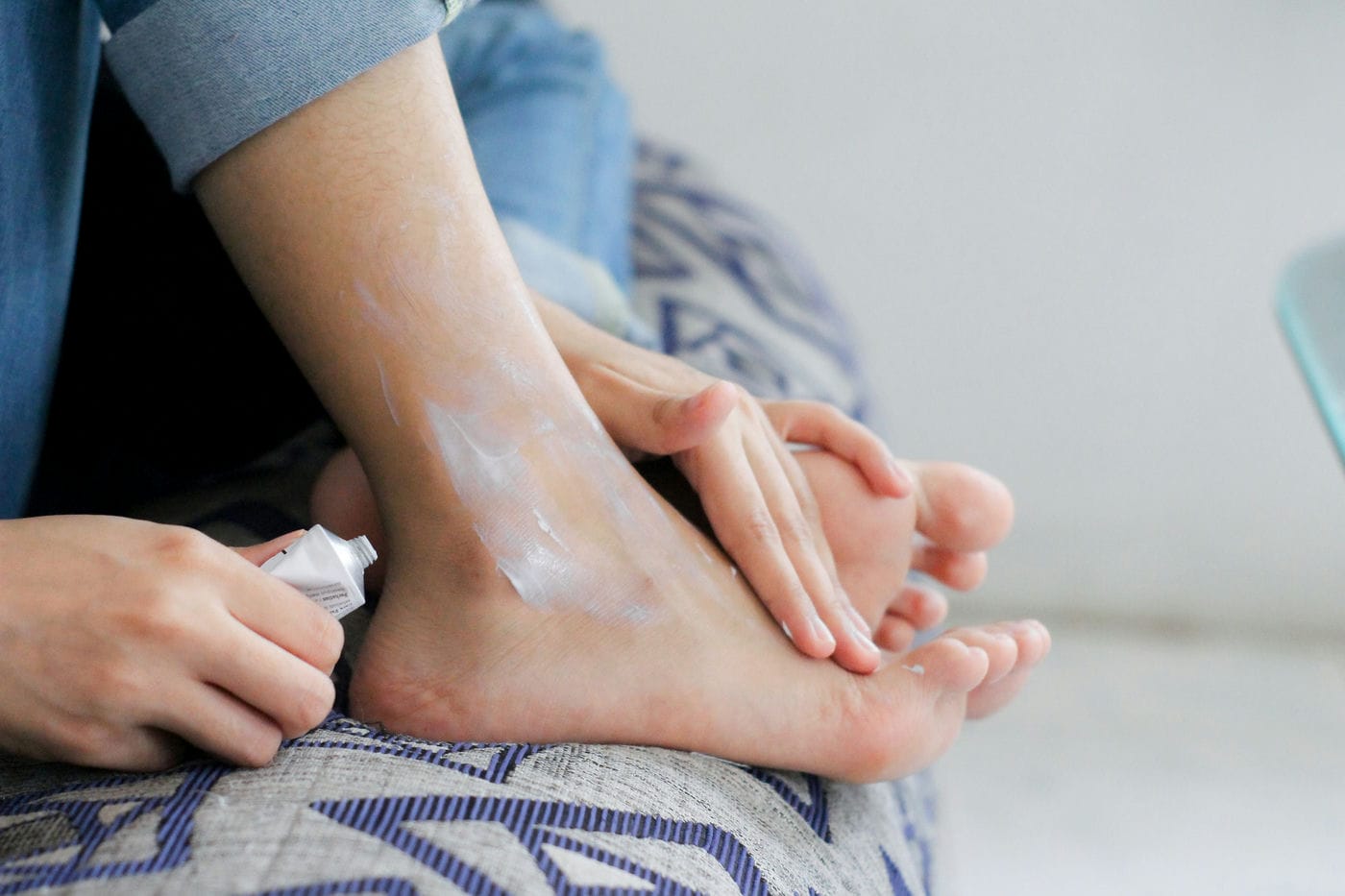 woman applying medicinal cream on her foot