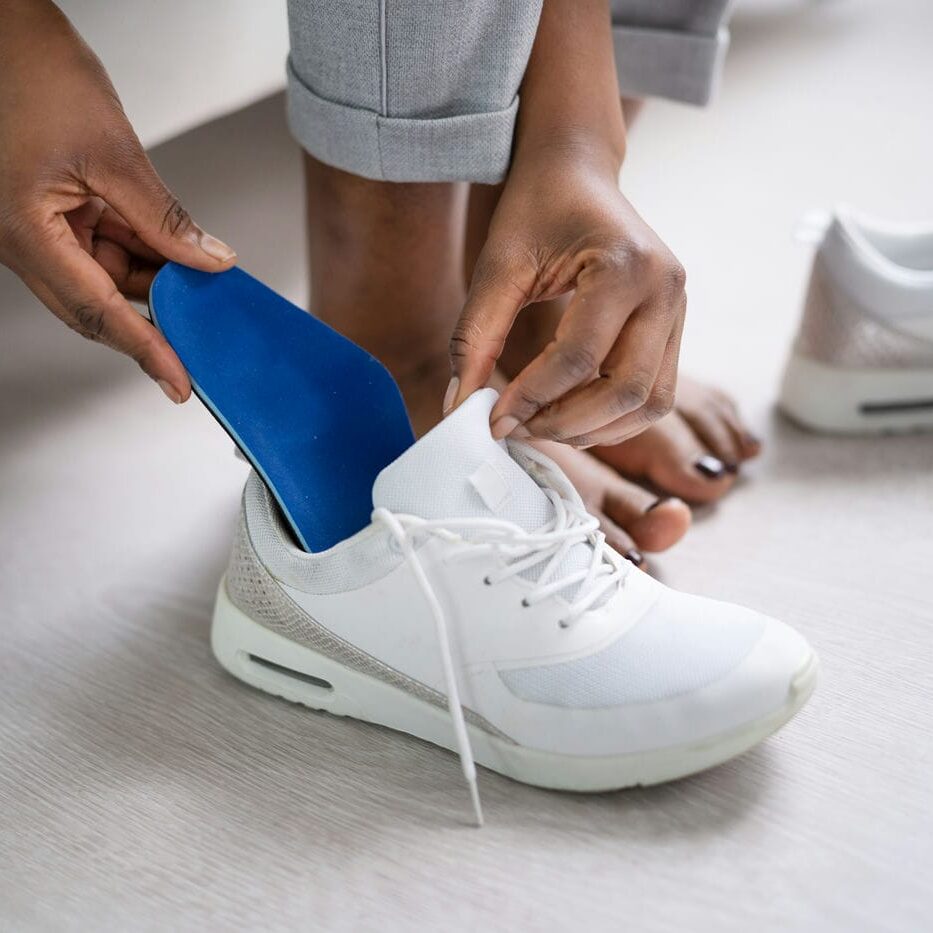man inserting his custom orthotics in his shoes